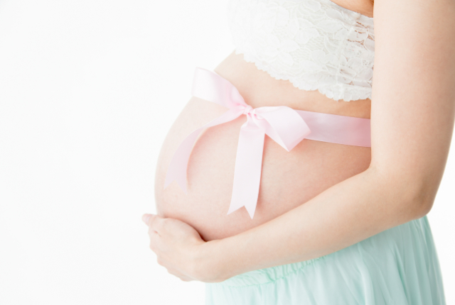 お腹にリボンを巻いた妊婦